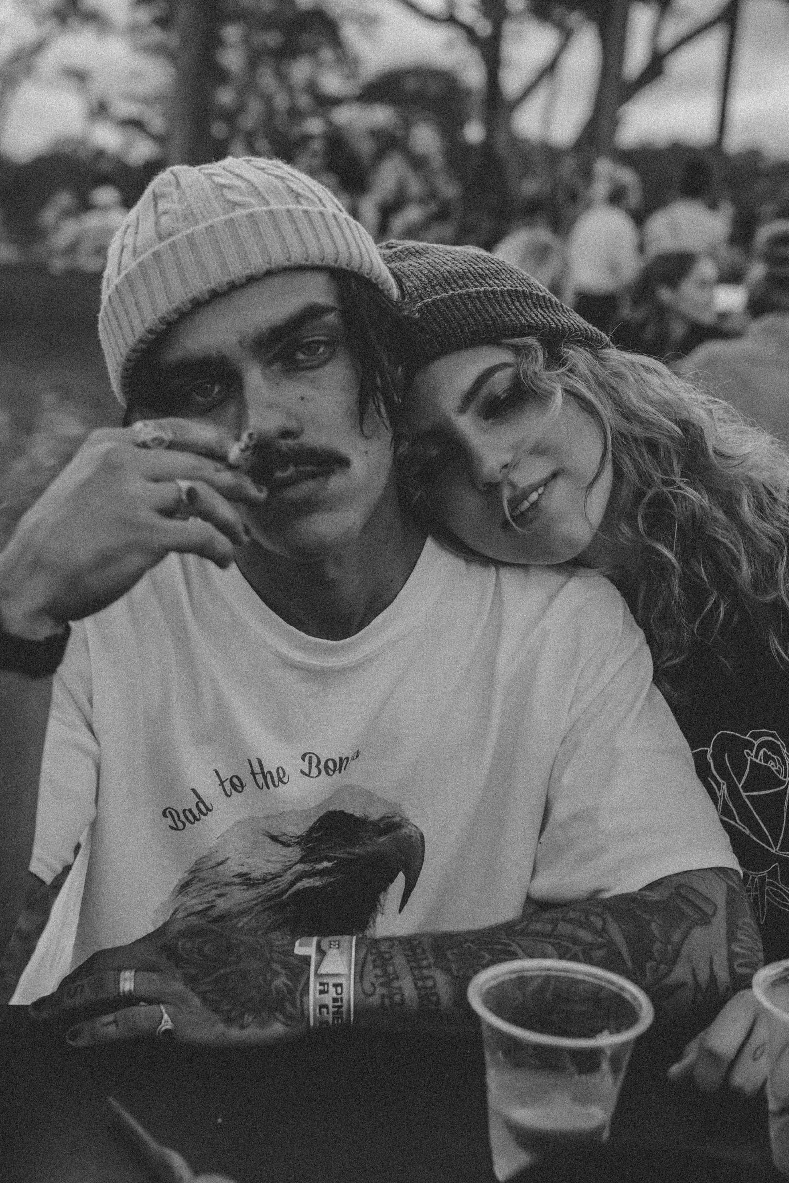 Black-and-white portrait of two people leaning together at an outdoor table.