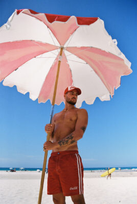 model bruno wearing coke x svs hat and shorts at beach topless