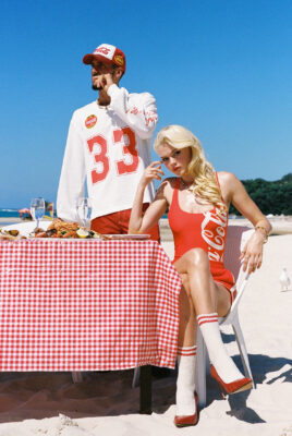 model ayla and bruno sitting at table on beach eating chips in coca cola x something very special outfits