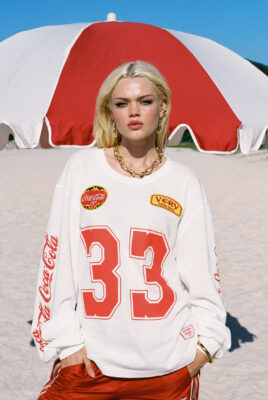 model ayla at beach in front of beach umbrella wearing 33 coke x svs shirt